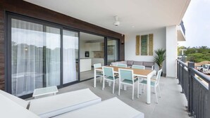 A modern balcony with a dining area, sliding glass doors, and a view of the interior kitchen. - The Breeze at Blue Bay Beach & Golf Resort (Sint Michiel)