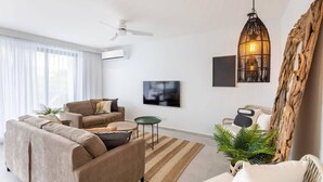 A modern living room with a sofa, coffee table, and a hanging light fixture. - The Breeze at Blue Bay Beach & Golf Resort (Sint Michiel)