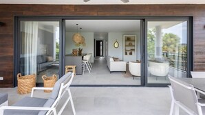 A modern interior with a dining area, sofa, and a balcony with a view.