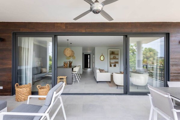 A modern interior with a dining area, sofa, and a balcony with a view.