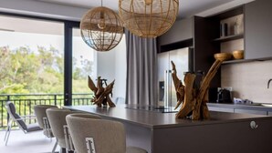 A modern kitchen with a central island, pendant lights, and a view of the outdoors.