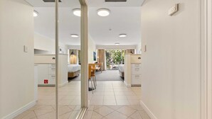 A hotel corridor with mirrored walls, a central seating area, and a view of a garden through the windows.