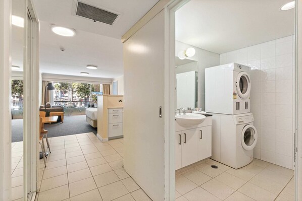 A modern bathroom with a washing machine, a sink, and a mirror. - Manly Seabreeze (Manly)