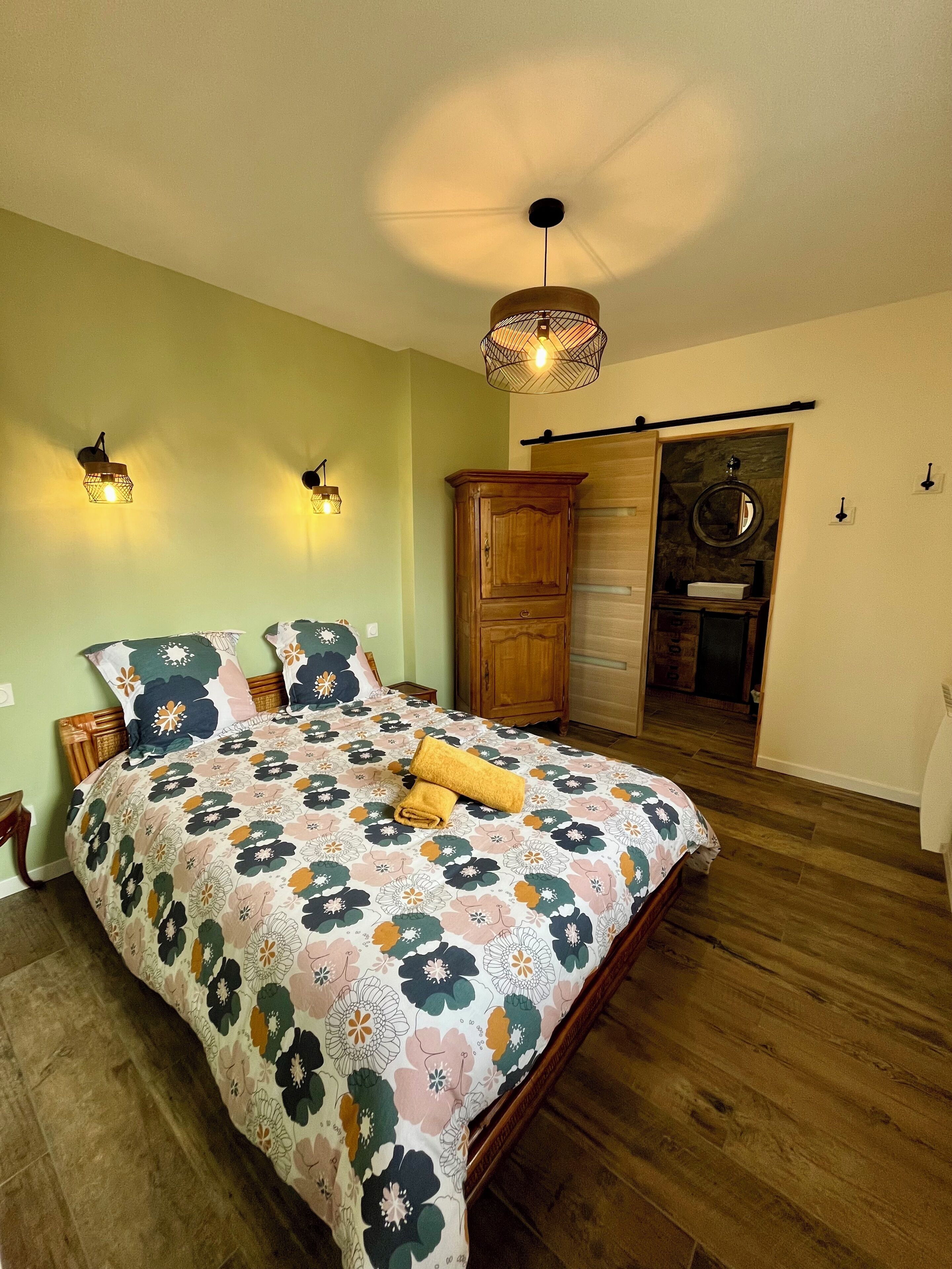 A bedroom with a floral bedspread, wooden headboard, and a wooden wardrobe.