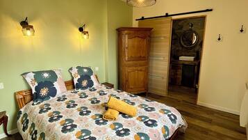 A bedroom with a floral bedspread, wooden headboard, and a wooden wardrobe.