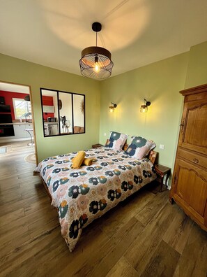 Une chambre à coucher avec une couvre-lit à motifs floraux, une tête de lit en bois et une armoire en bois.