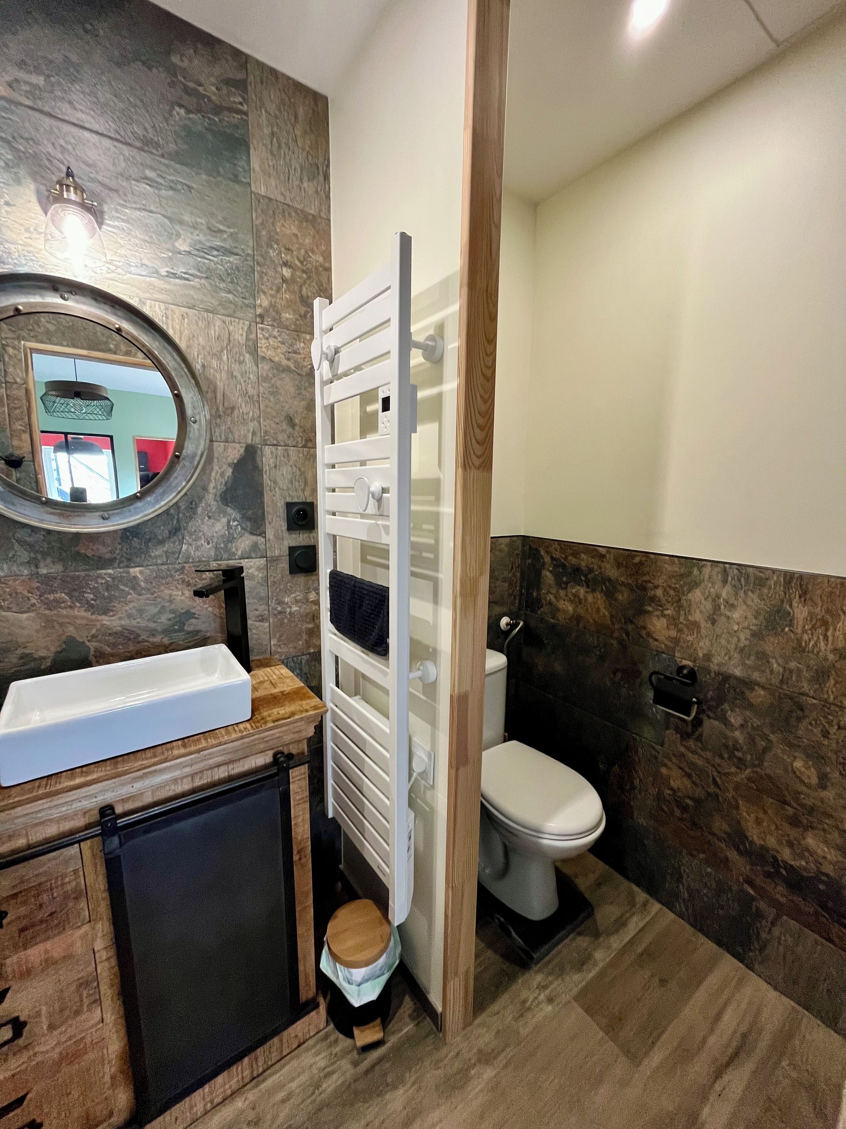 A bathroom with a modern design, featuring a white sink, a toilet, and a towel rack.