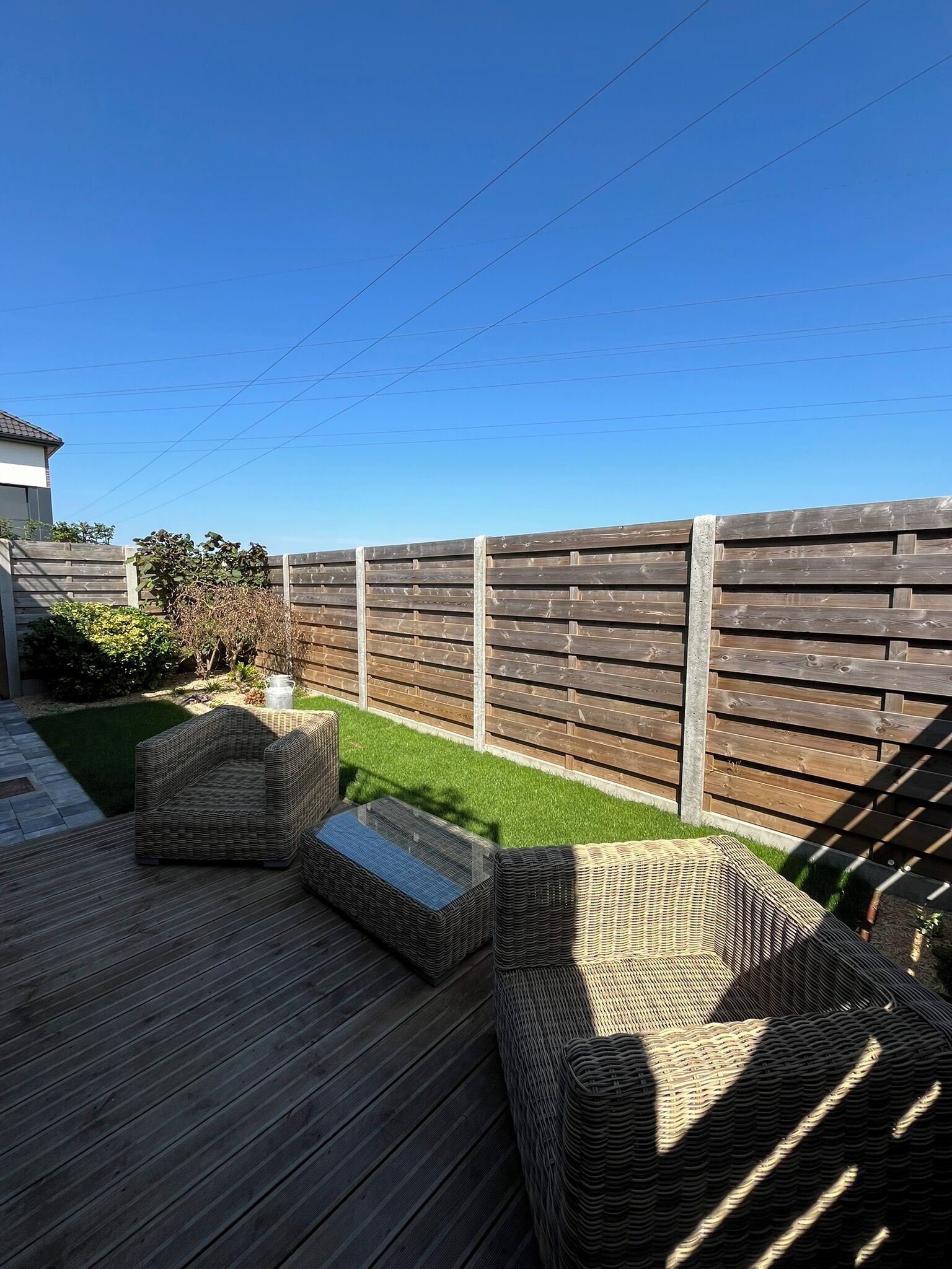A wooden deck with wicker furniture and a small lawn area.