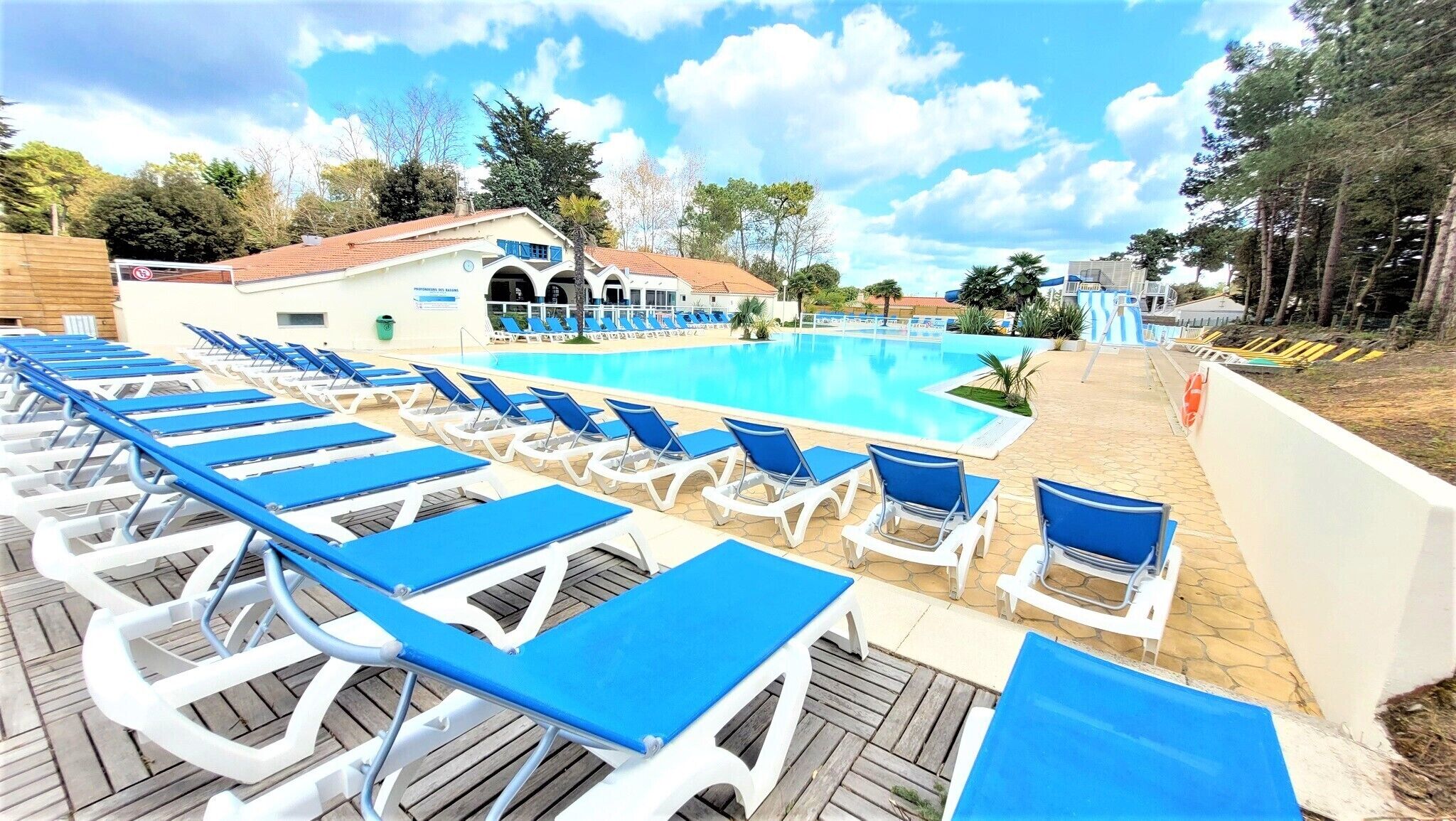 A poolside area with sun loungers and a building with a tiled roof.
