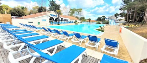 A poolside area with sun loungers and a building with a tiled roof.