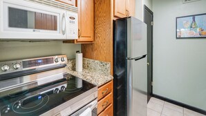 A kitchen with wooden cabinets, a stainless steel stove, a black refrigerator, and a microwave. - 3 Mi to Dtwn Dallas: Condo w/ Walkable Location! (Dallas)