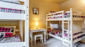 A bunk bed room with a desk and chair, a lamp, and a motivational poster on the wall.