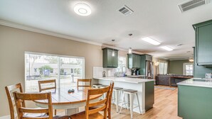 A modern kitchen with a central island, wooden chairs, and a dining table.