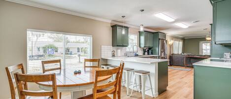 Una cocina moderna con una isla central, sillas de madera y una mesa de comedor.