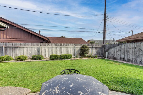 A backyard with a wooden fence, a lawn, and a metal table. - ~ 2 Blocks to Beach: Galveston Group Getaway! (Galveston)