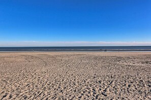 A wide sandy beach with footprints leading towards the water.