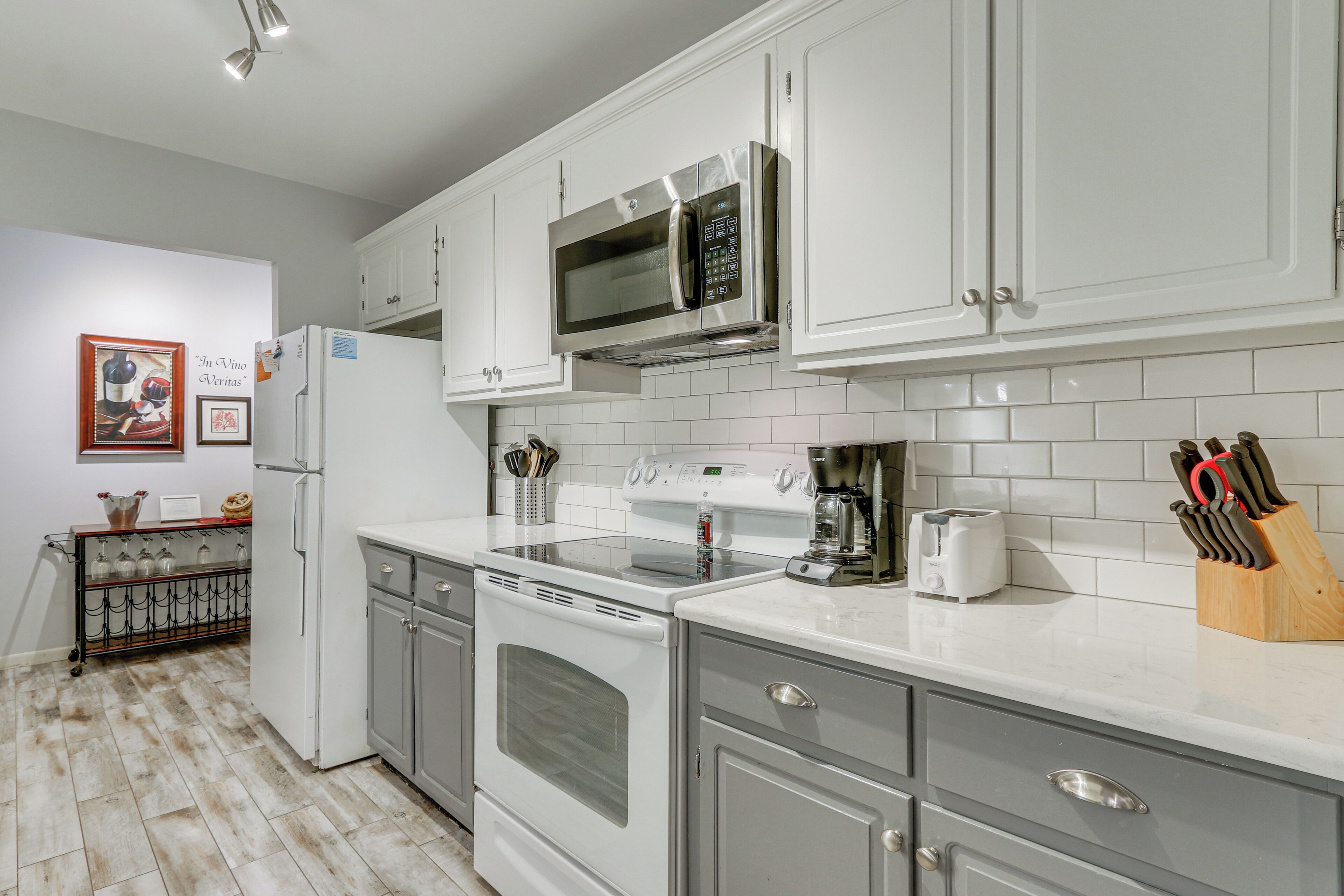 A modern kitchen with white cabinets, stainless steel appliances, and a tiled backsplash.