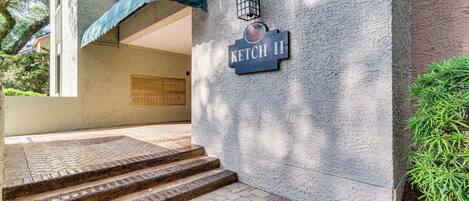 A building entrance with a sign reading "KETCH II," a covered staircase, and a lantern.