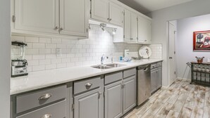 Une cuisine moderne avec des meubles blancs, un plan de travail blanc et un revêtement mural en carreaux.