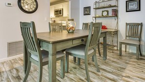 Une salle à manger avec une table en bois, des chaises, une horloge et une étagère décorative.