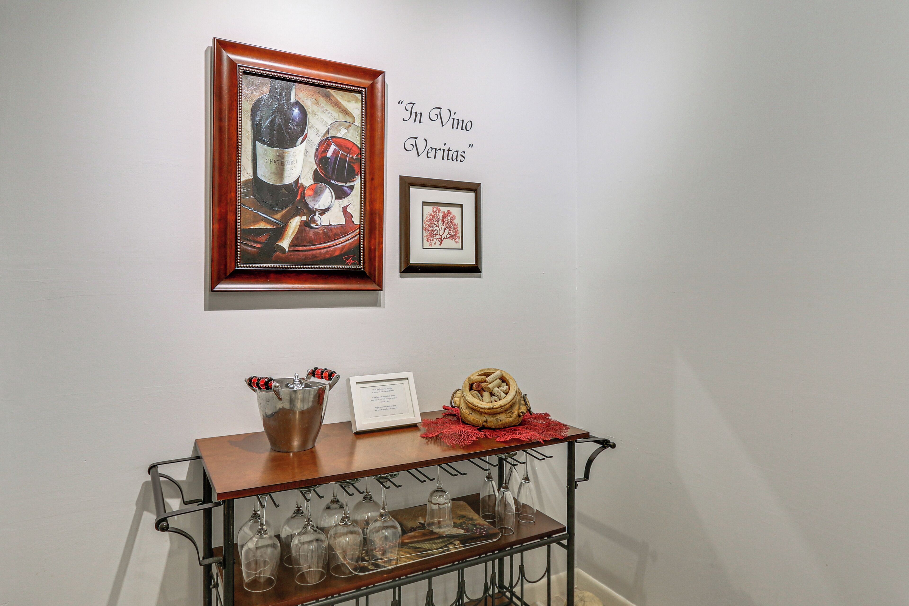 Esposizione di vino con un quadro incorniciato, un tavolino con un cesto e una cantina con bicchieri.