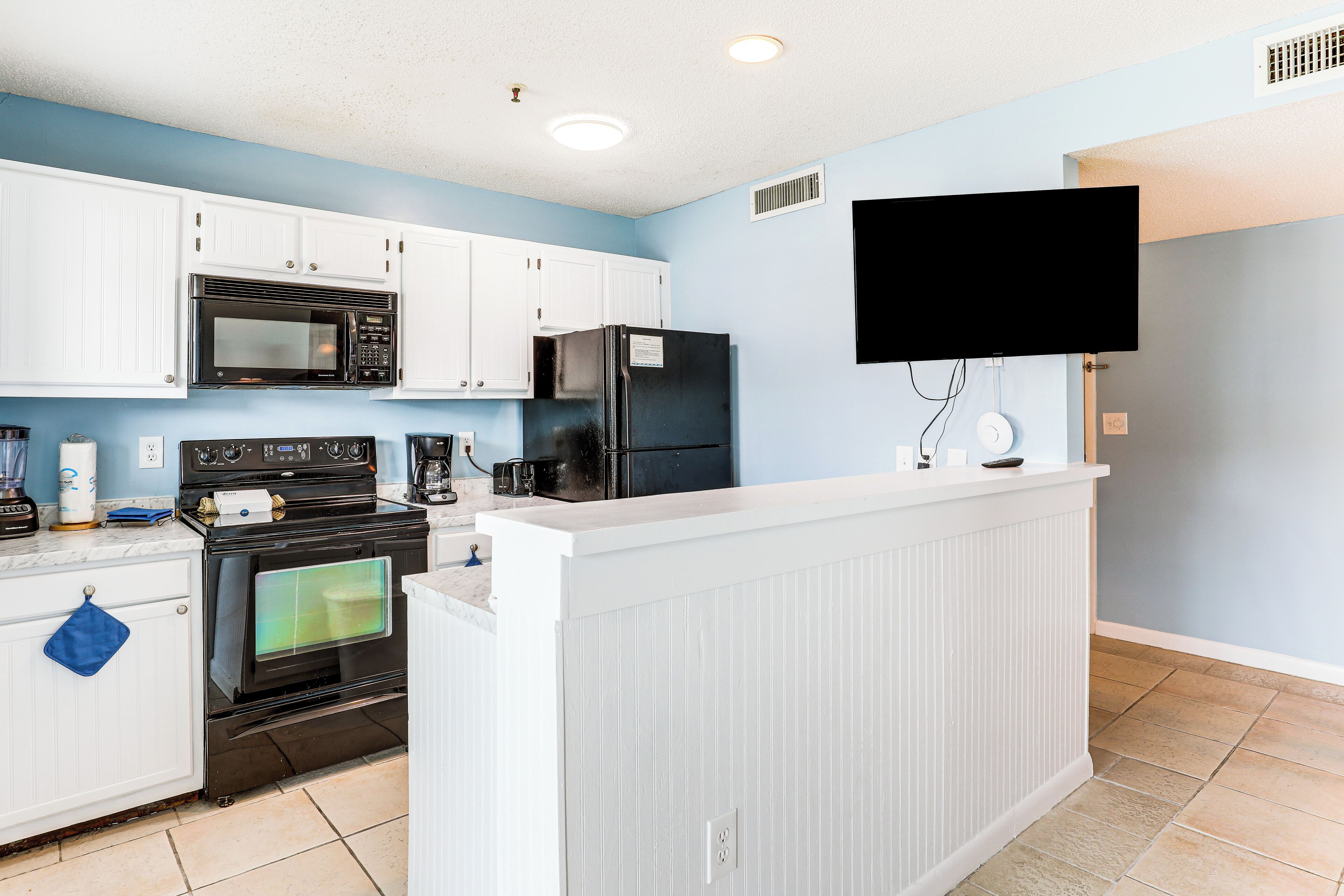 A kitchen with white cabinets, a black microwave, a black refrigerator, and a built-in oven.