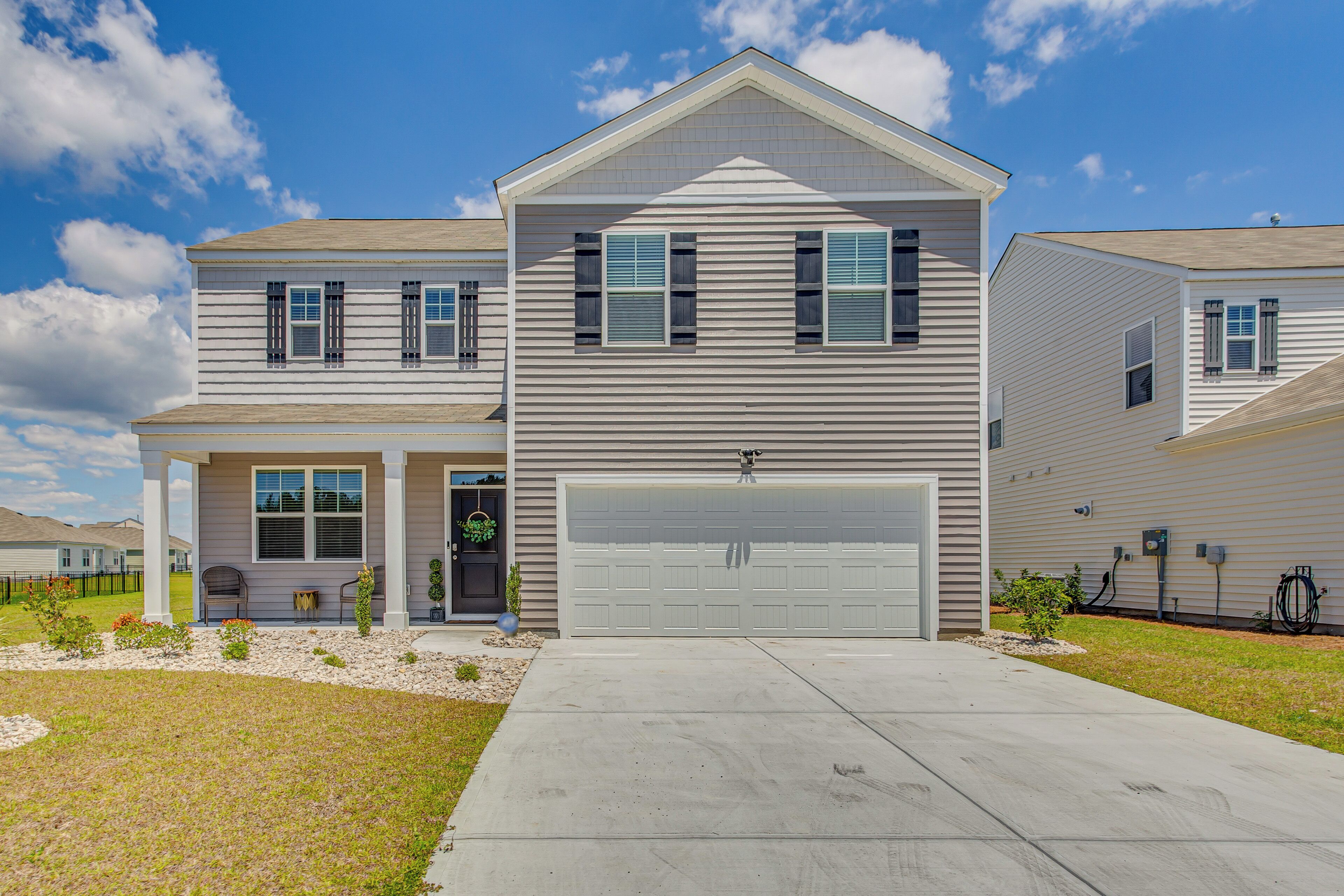 A two-story residential house with a garage, a front porch, and a small garden area.