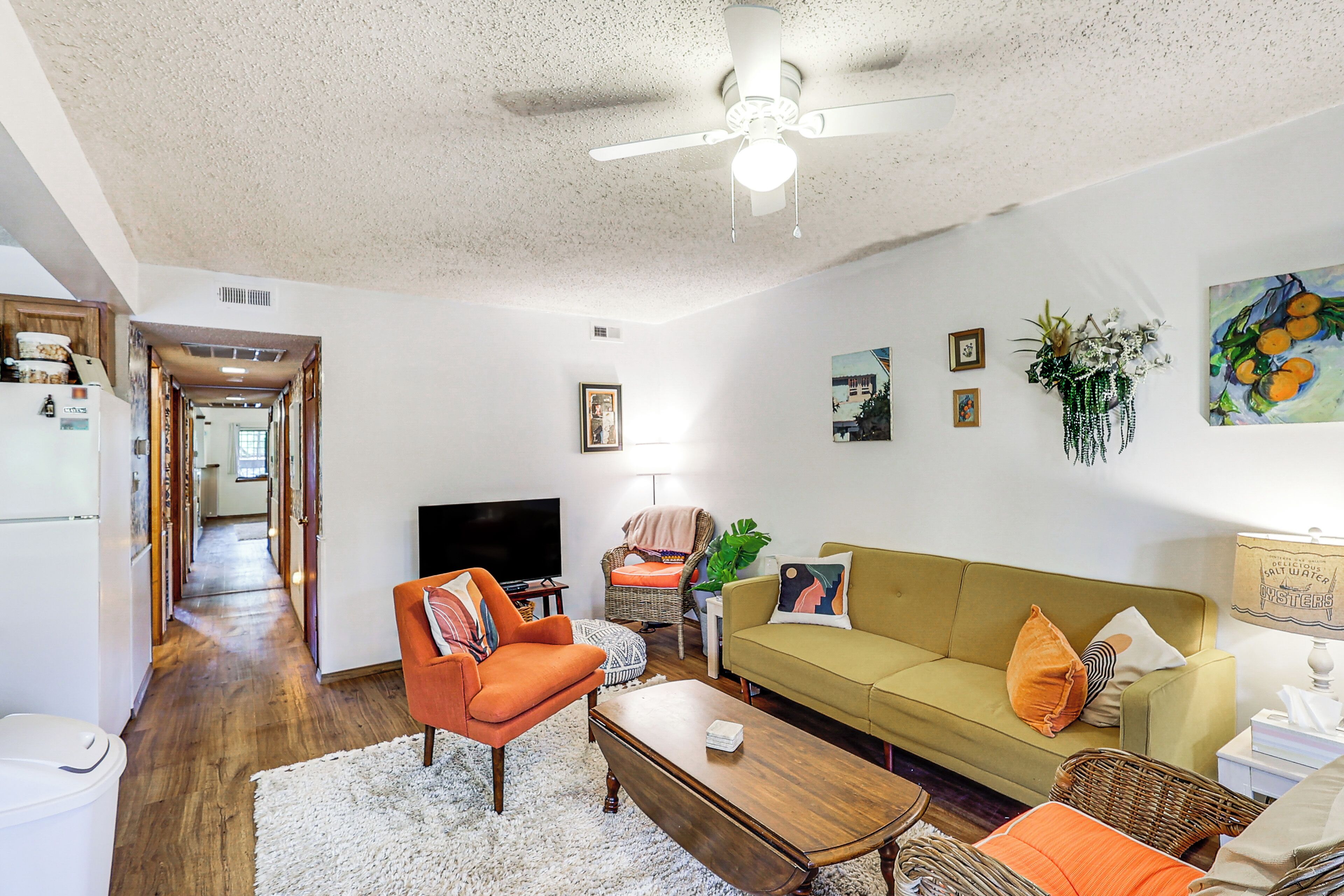 Een woonkamer met een bank, fauteuil, salontafel en een televisie.