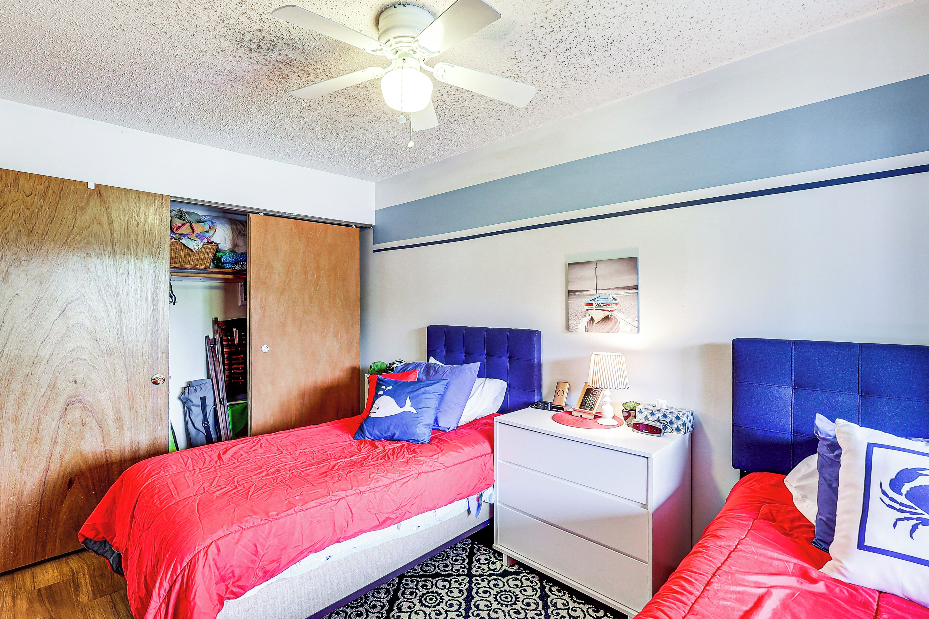 A bedroom with a bed, a nightstand, a wardrobe, and a ceiling fan.
