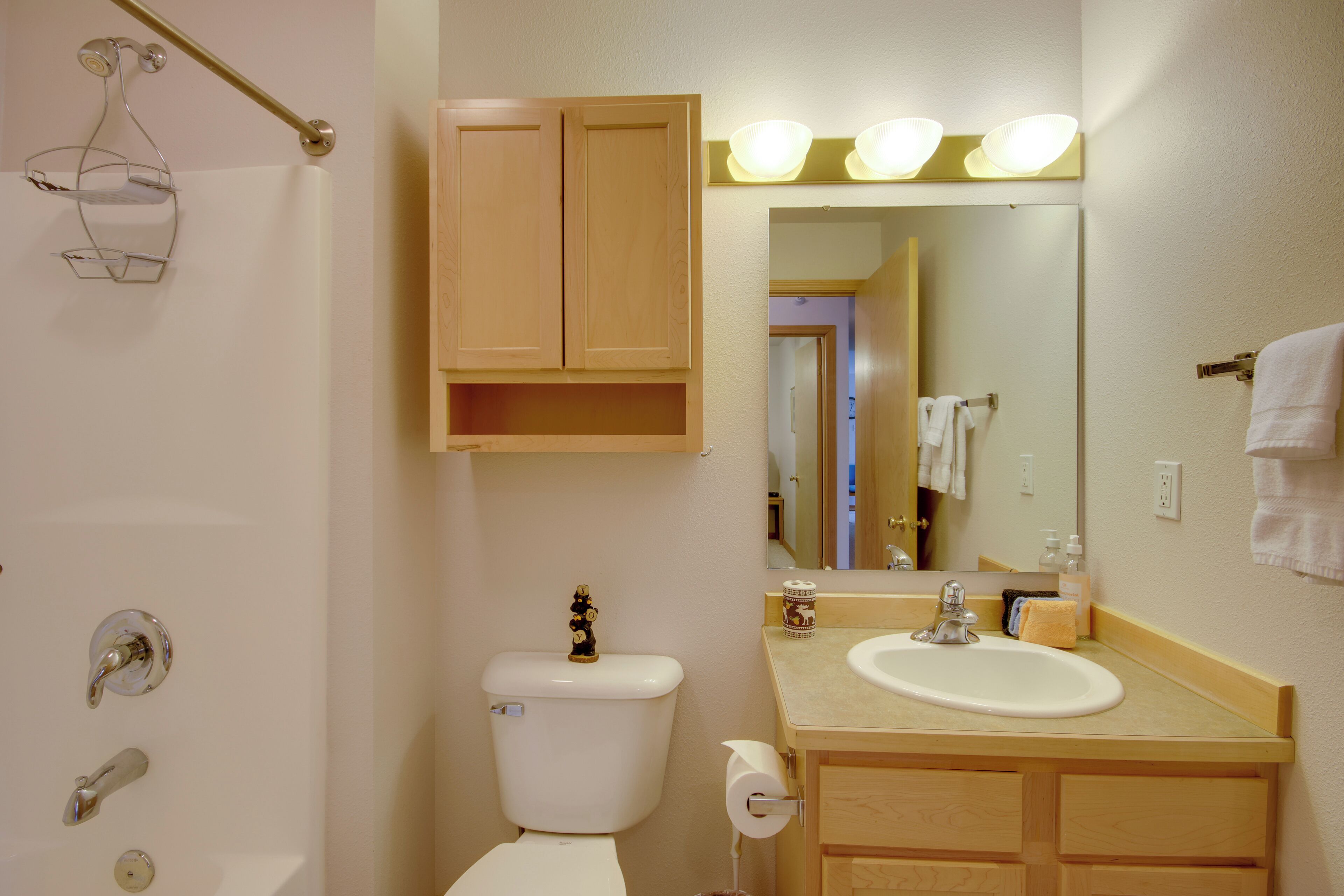 A bathroom with a toilet, sink, mirror, and towel rack.