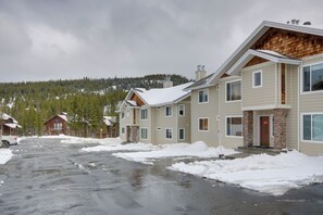 Um bairro residencial com várias casas de dois andares, um acesso pavimentado e uma paisagem nevada com árvores ao fundo.