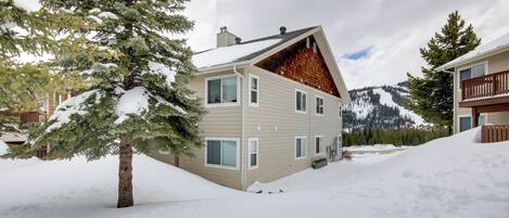 A multi-story building with a sloped roof, surrounded by snow-covered ground and trees.