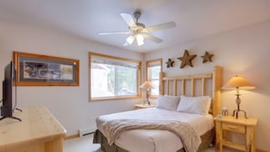 Un dormitorio con cama, escritorio, ventilador de techo, ventana y decoración con estrellas en la pared.