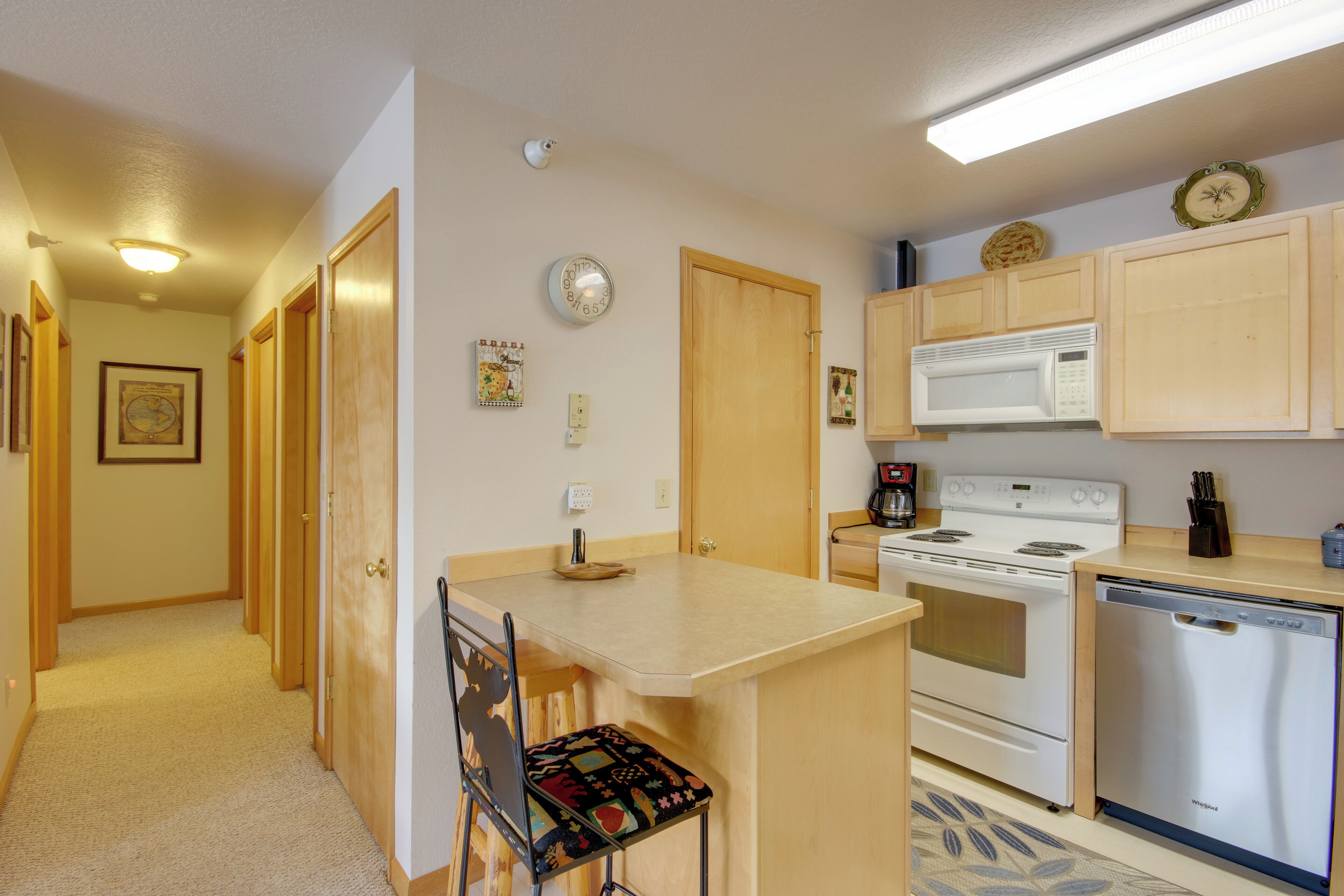 A compact kitchen with wooden cabinets, a microwave, a stove, and a dishwasher.