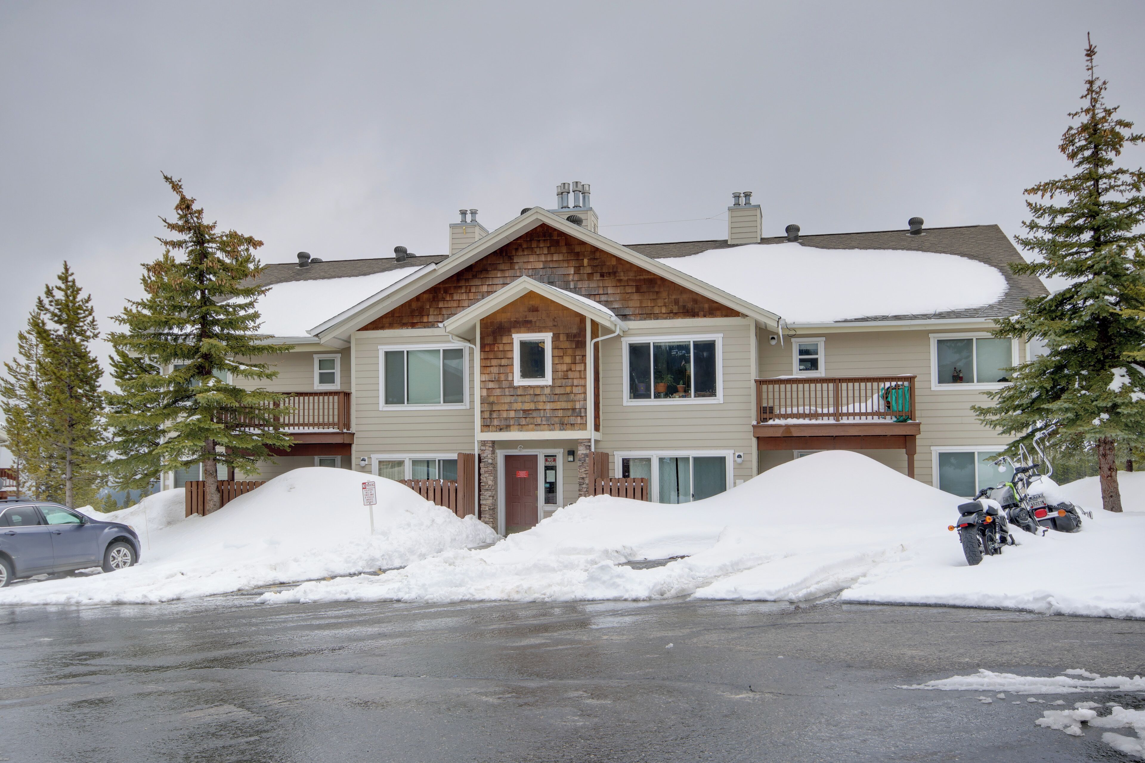 A two-story building with a wooden facade and multiple windows. There is snow on the roof and around the building.
