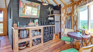 Una cocina rústica con estantes de madera, una cafetera y un refrigerador.