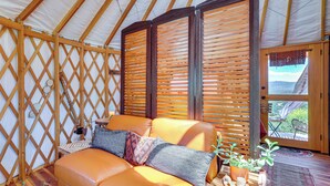 Un interior acogedor con un sofá de cuero, persianas de madera y vistas al exterior.
