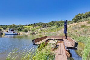 A wooden dock extending into a calm river, with a boat docked nearby and a clear blue sky above. - Mystical Mongolian Yurt in Fallbrook w/ Views! (Fallbrook)