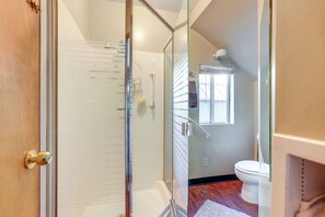 Ein Badezimmer mit Glasdusche, Toilette und Fenster.