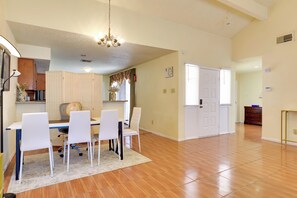 A spacious dining area with a wooden floor, white chairs, and a glass table. - Houston Area Home w/ Yard - 5 Mi to Sugar Lakes! (Stafford)