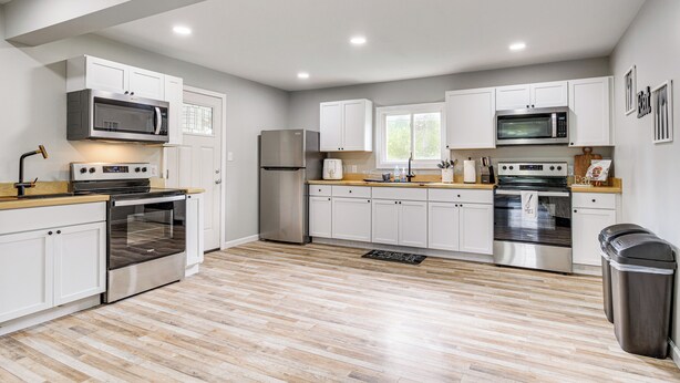 Una cocina moderna con armarios blancos, electrodomésticos de acero inoxidable y suelo de madera.