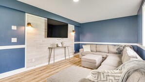 Una sala de estar moderna con un sofá modular, una mesita y un televisor montado.