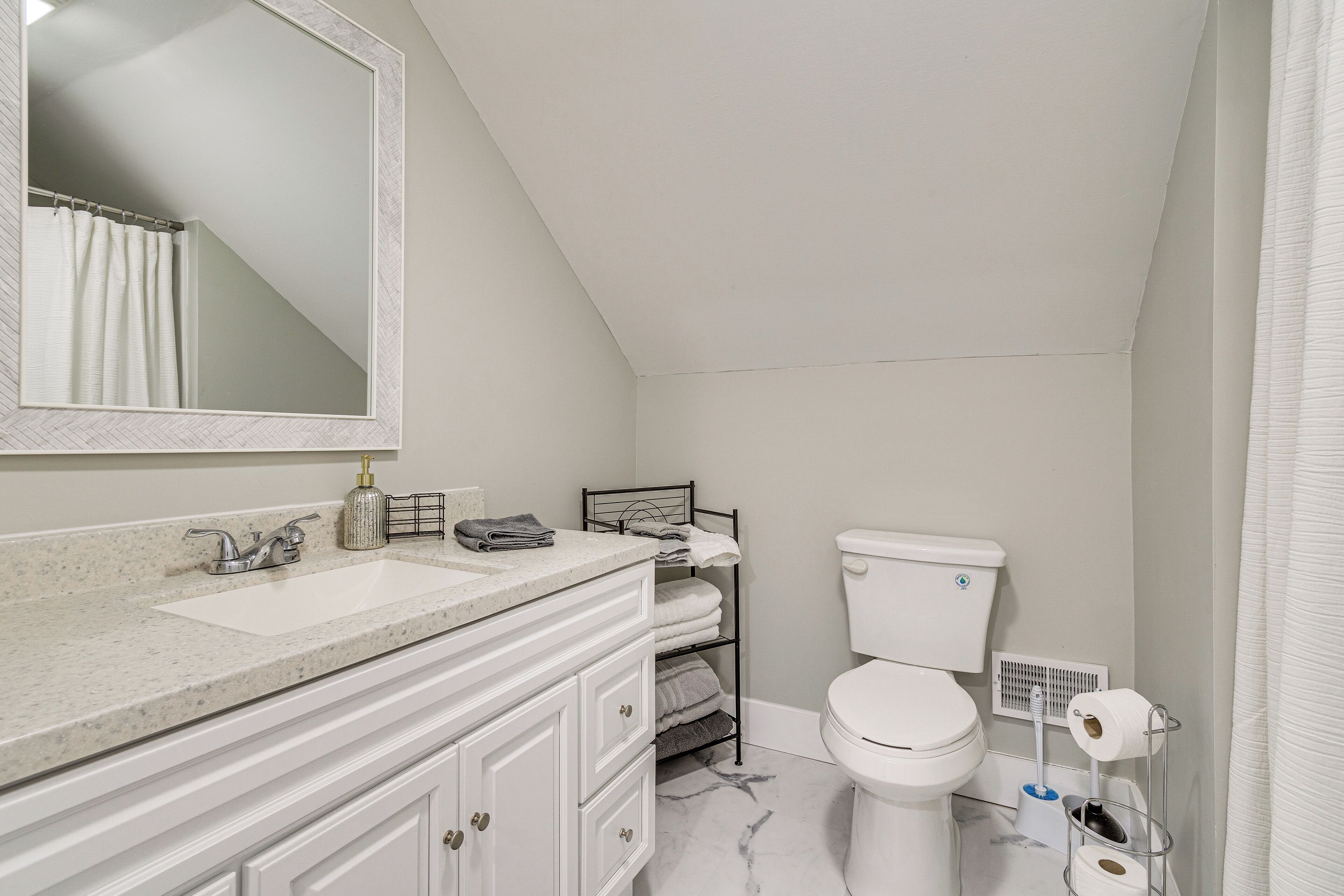 A bathroom with a white sink, a mirror, a toilet, and a shower curtain.