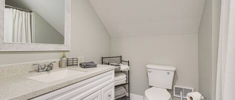 A bathroom with a white sink, a mirror, a toilet, and a shower curtain.
