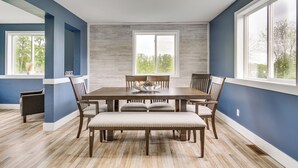Un comedor con una gran mesa de madera, seis sillas y un banco.