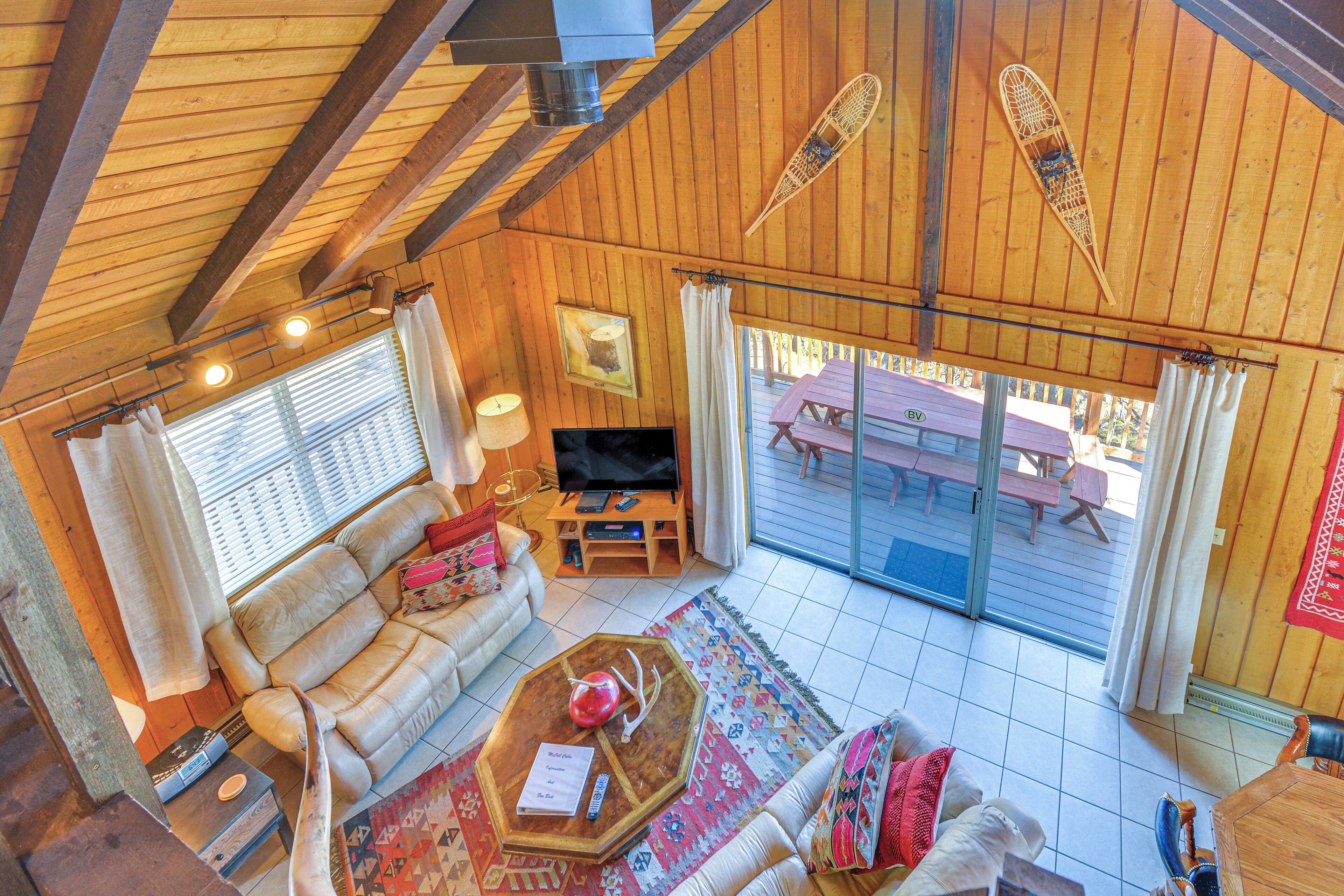 A cozy living room with a wooden ceiling, a sofa, a coffee table, and a TV.