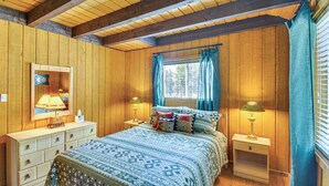 A bedroom with wooden walls, a bed with patterned bedding, two bedside tables with lamps, and a window with curtains. - 'mccall Creekside Cabin' Secluded Buena Vista Gem! (Buena Vista)