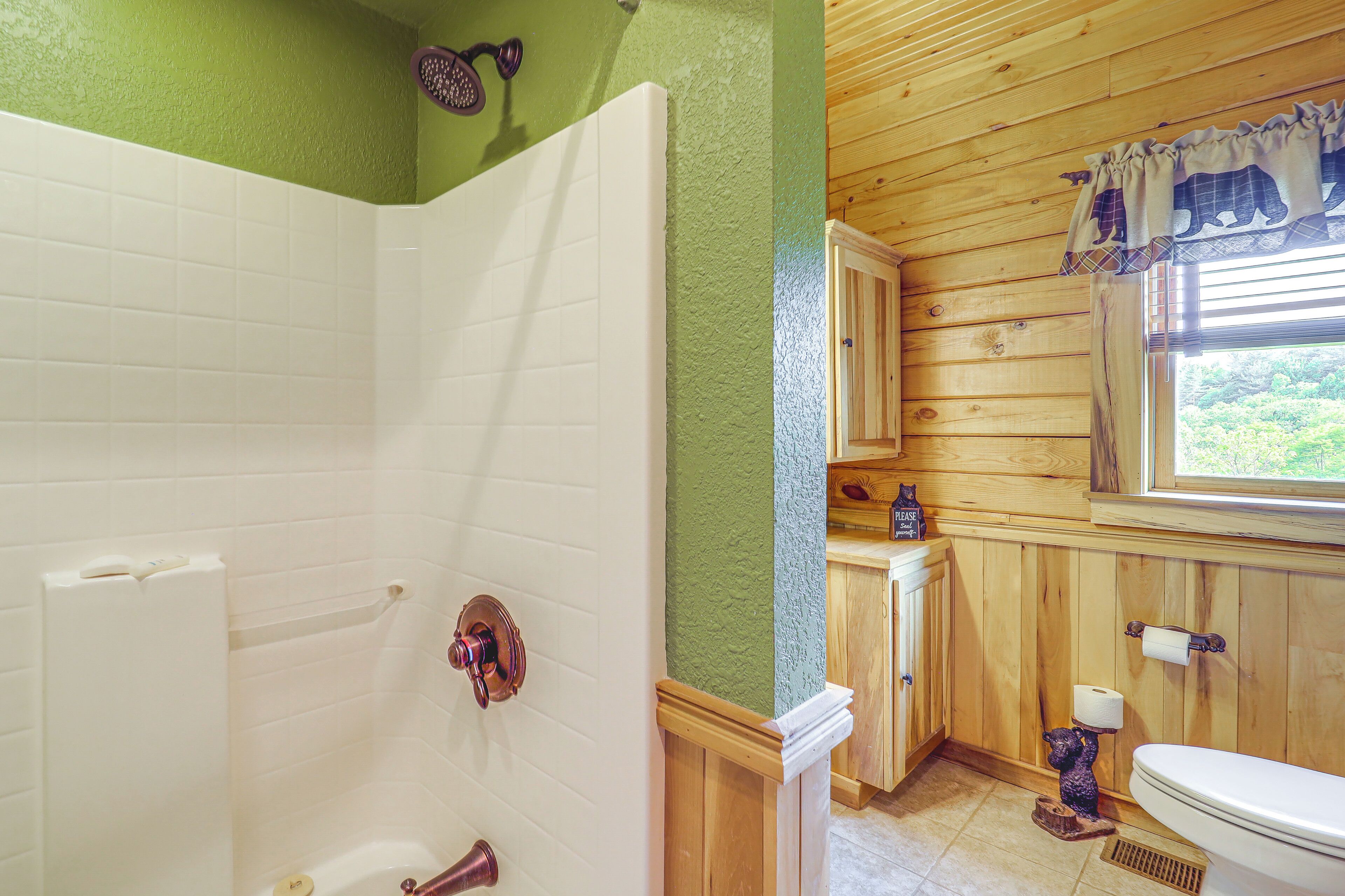 A bathroom with a shower, toilet, and wooden cabinets.
