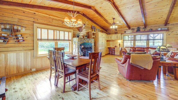 A wooden cabin interior with a dining area, a fireplace, and a living room with a sofa and a coffee table. - 4 Mi to Grandfather Mtn! Family-friendly Cabin (Newland)