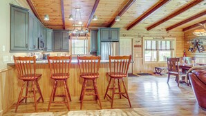 A spacious kitchen with wooden cabinets, a central island with bar stools, and a dining area with a wooden table and chairs. - 4 Mi to Grandfather Mtn! Family-friendly Cabin (Newland)